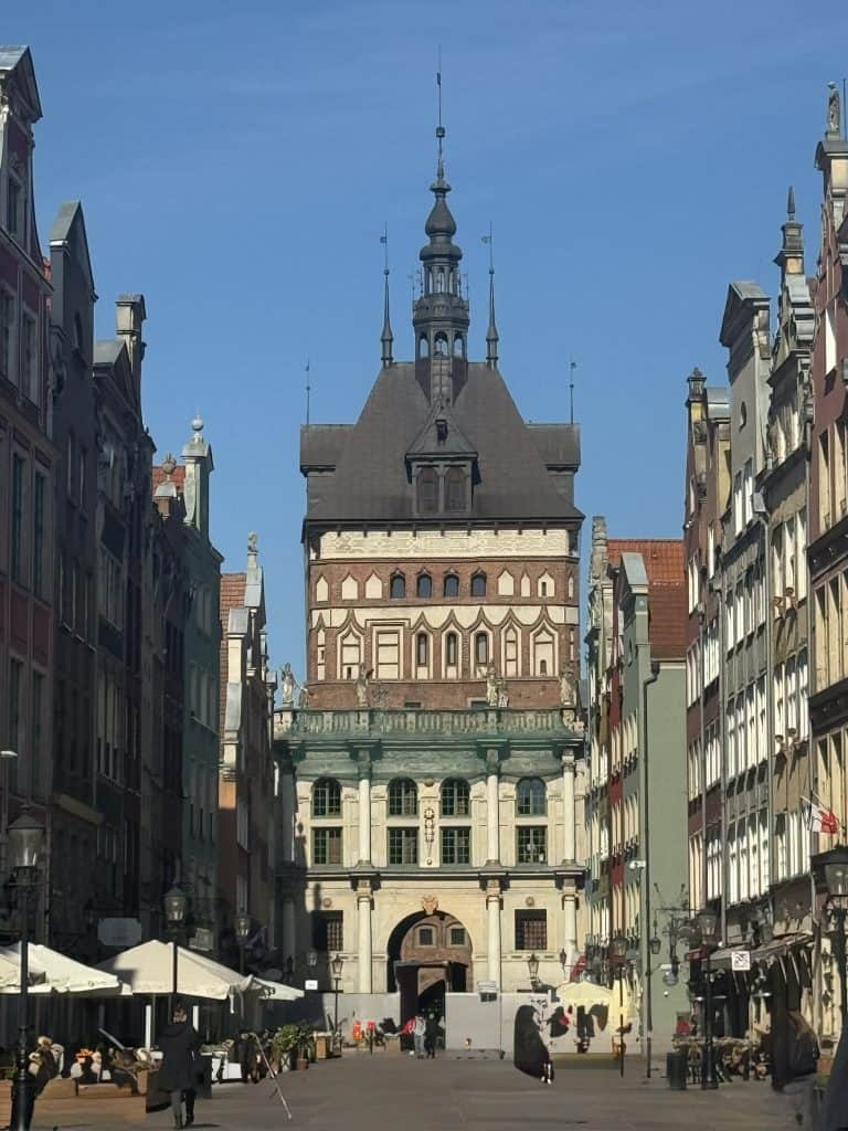 Prison Tower in Gdańsk’s Old Town, with its ornate spire and colorful facades, framed by historic buildings under a bright blue sky.