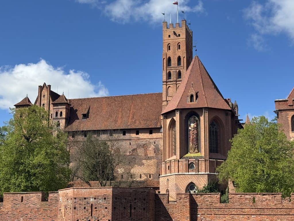Historic section of Malbork Castle in Poland showing medieval red brick towers and fortified walls with a clear sky backdrop
