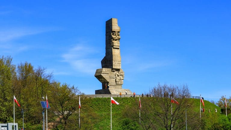Westerplatte Monument in Gdańsk, Poland, standing tall on a grassy hill under a clear blue sky, commemorating the Polish defenders of the 1939 battle that marked the start of World War II.