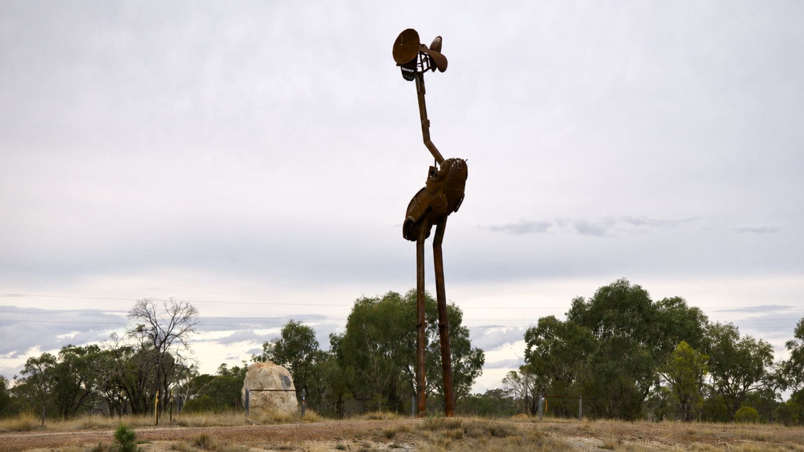 Stanley the emu sculpture near Lightning Ridge, Australia — tall rusted metal artwork standing in an open outback landscape under a cloudy sky.